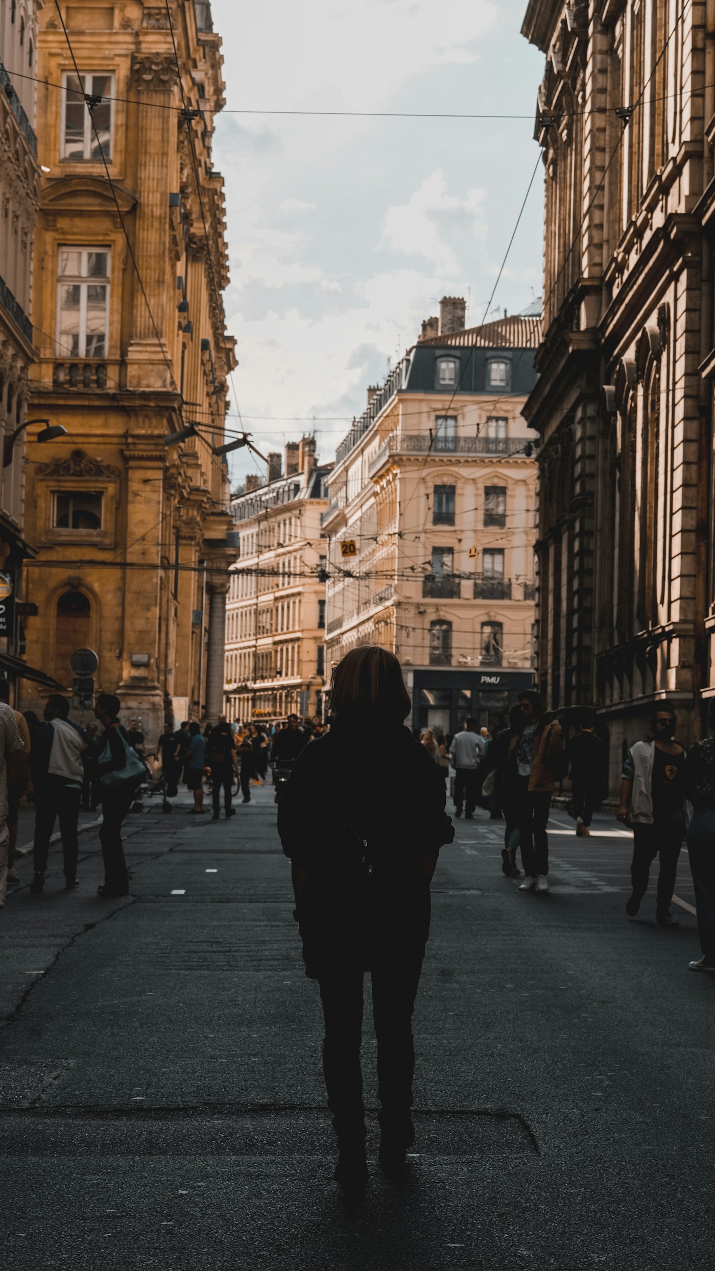Pedestrians walking between historic stone buildings on a city street